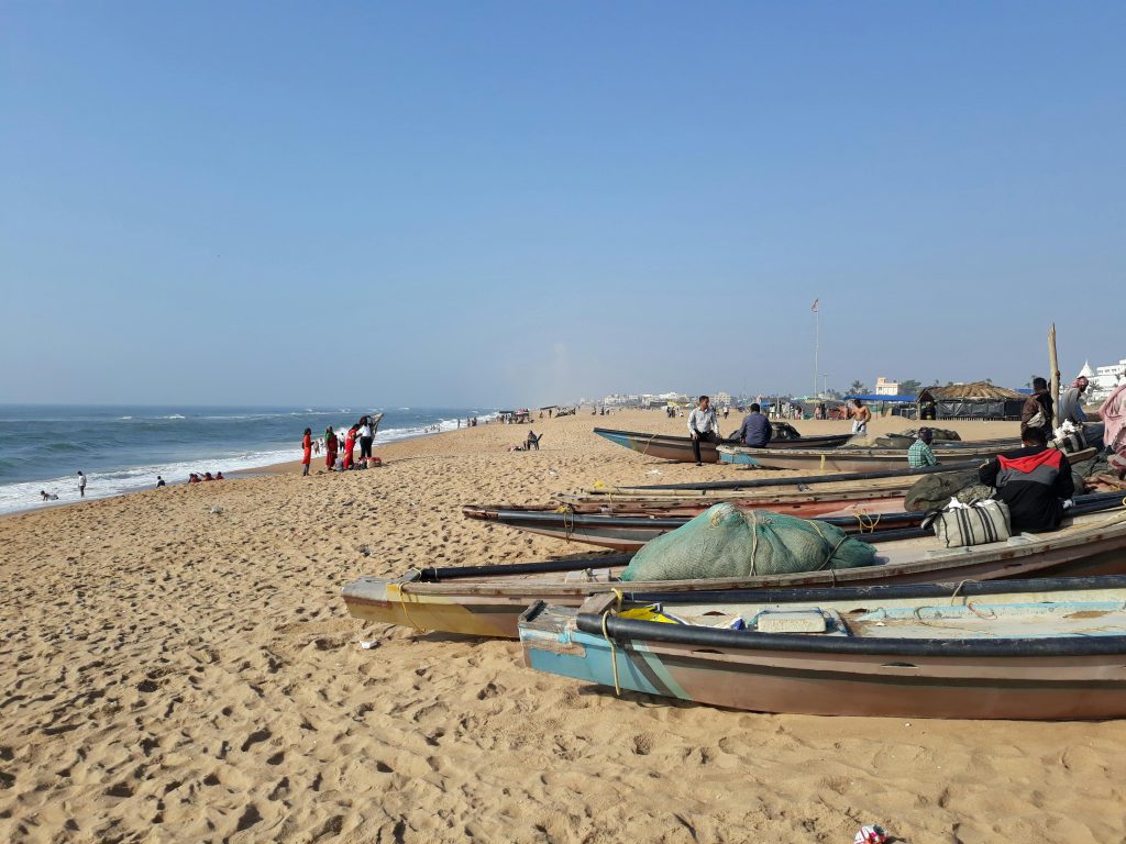 A vibrant day at Puri's coast with boats and people enjoying the scenic beach.